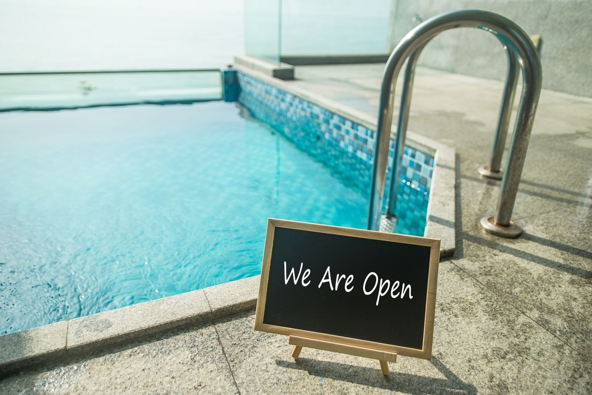 Blackboard with text we are open and swimming pool as a background Blackboard with text we are open and swimming pool as a background